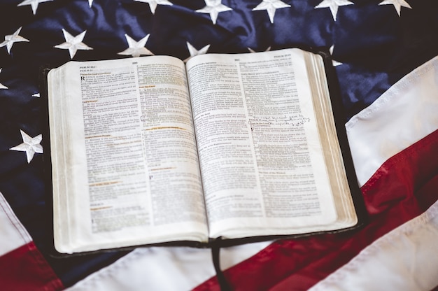 Close-up shot van de bijbel geopend in pagina's op de amerikaanse vlag - perfect voor bidden concept