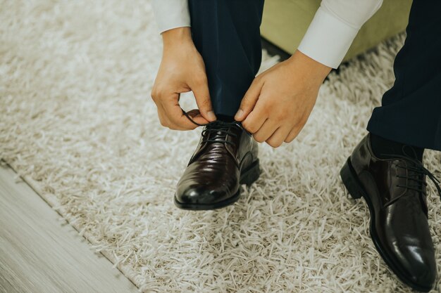 Close-up shot van de bruidegom die de veters aan schoenen vastmaakt