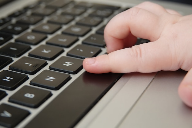 Close-up shot van de hand van een baby op een computertoetsenbord