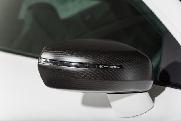 Close-up shot van de zwarte zijspiegel van een moderne witte auto