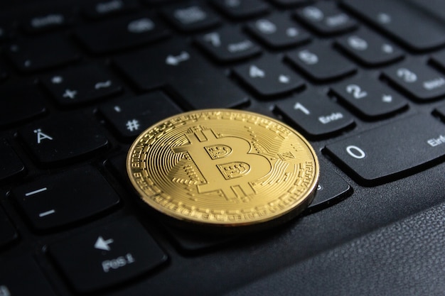 Close-up shot van een bitcoin op een zwart computertoetsenbord