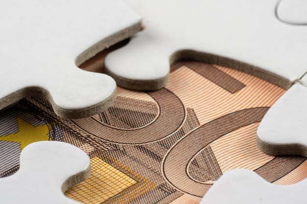 Close-up shot van een deel van geld gezien onder een verwijderd stuk van een puzzel