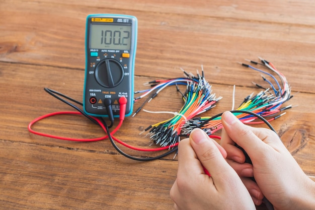 Gratis foto close-up shot van een digitale multimeter met veel kleurrijke draden op houten tafel