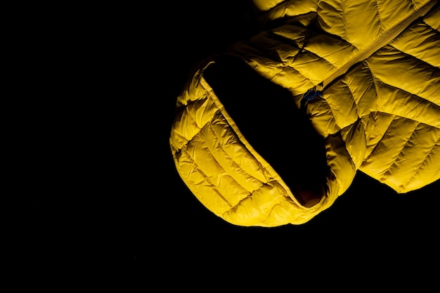 Close-up shot van een geel donsjack op zwarte achtergrond