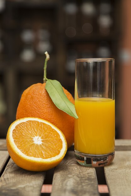 Close-up shot van een glas jus d'orange en verse sinaasappelen op een houten kist met wazig