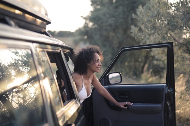 Close-up shot van een glimlachende jonge vrouw die naar buiten kijkt vanuit de auto