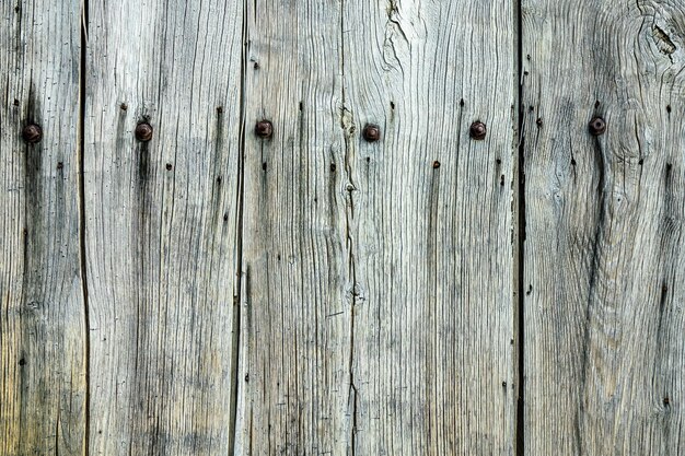 Close-up shot van een grijze houten muur met spijkers erop