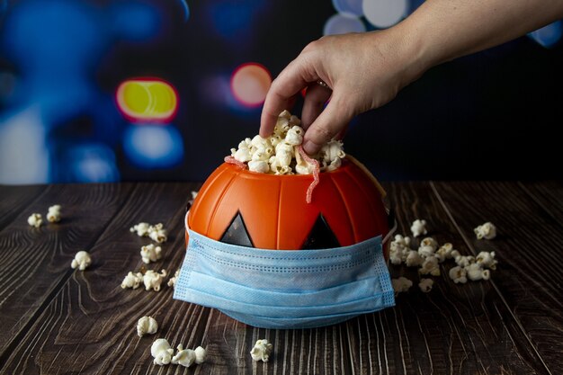 Close-up shot van een Halloween-pompoen met popcorn en een sanitair masker-concept van het nieuwe normaal