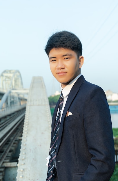 Close-up shot van een jonge aziatische man in een pak staande op een brug