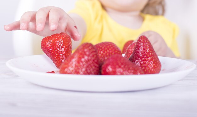 Close-up shot van een klein meisje dat aardbeien eet