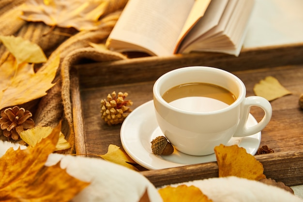 Close-up shot van een kopje koffie en herfstbladeren op houten oppervlak