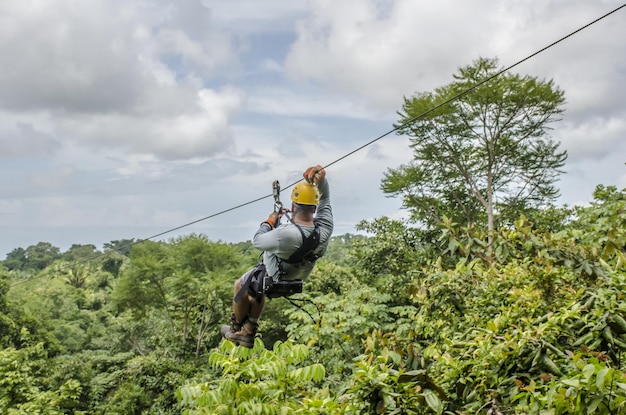 Close-up shot van een man die aan de zipline hangt en glijdt in een prachtige bewolkte hemel in een park