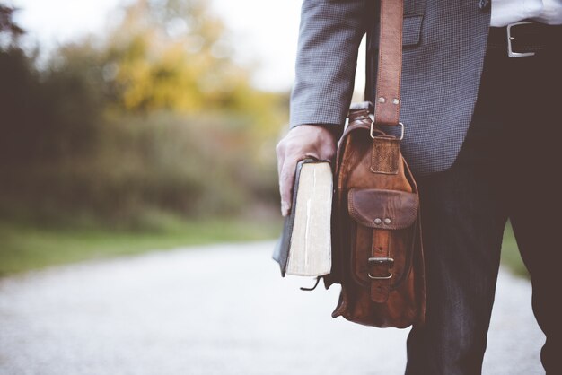Close-up shot van een man die een tas draagt en de bijbel verstopt