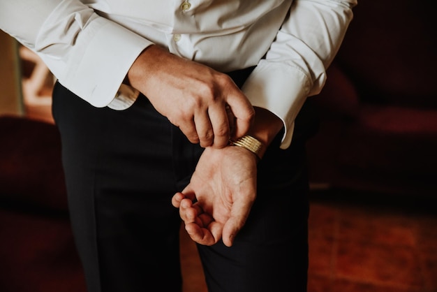 Gratis foto close-up shot van een man in een elegant shirt die zijn horloge afstelt