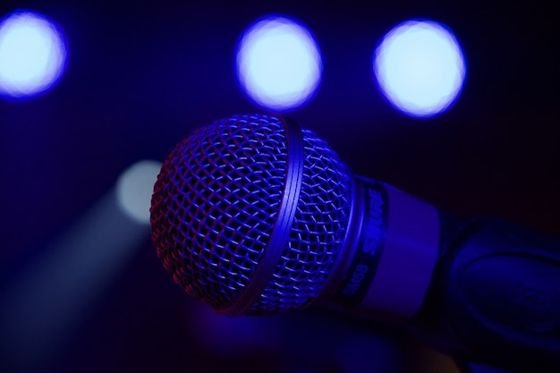 Close-up shot van een microfoon op een podium tijdens een evenement met lichten op de achtergrond