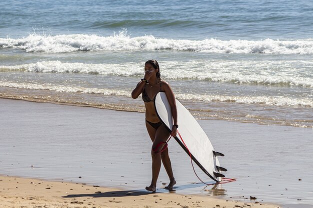 Close-up shot van een mooie jonge dame met een surfplank op het strand