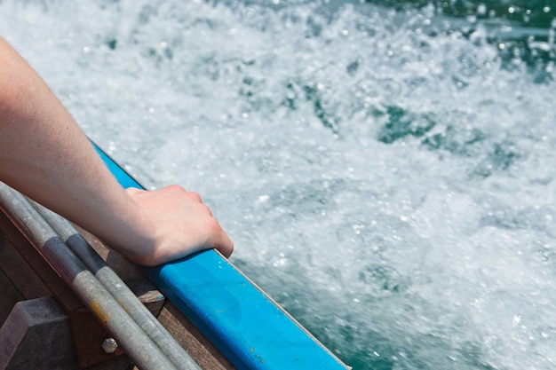 Gratis foto close-up shot van een persoon die zijn hand op het schip op zee legt