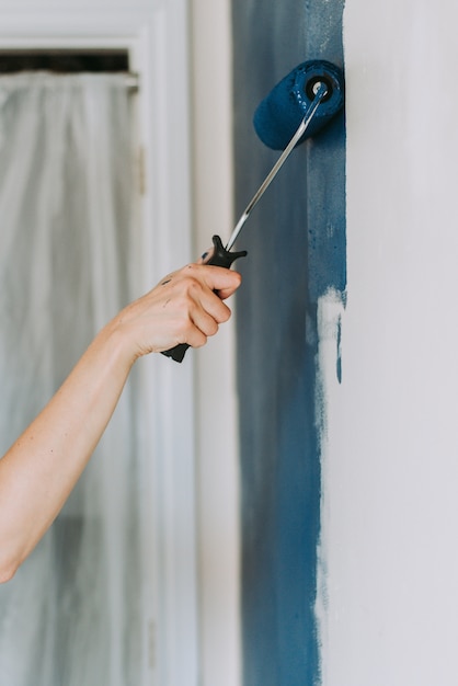 Gratis foto close-up shot van een persoon met verfrollen met de kleur blauw