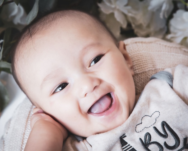 Close-up shot van een schattige blanke babyjongen, omringd door bloemen