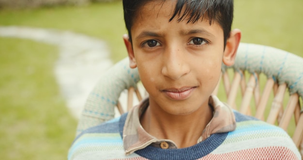 Close-up shot van een Zuid-Aziatische jongen die serieus zit te kijken in de tuin van het huis in India