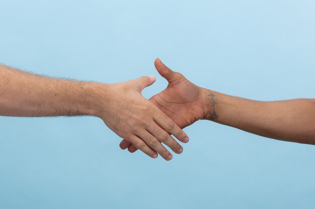 Close-up shot van menselijke hand in hand geïsoleerd op blauw