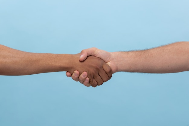 Close-up shot van menselijke hand in hand geïsoleerd op blauw