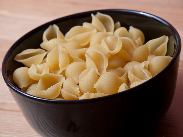 Close-up shot van ongekookte pasta gegoten in een zwarte kom