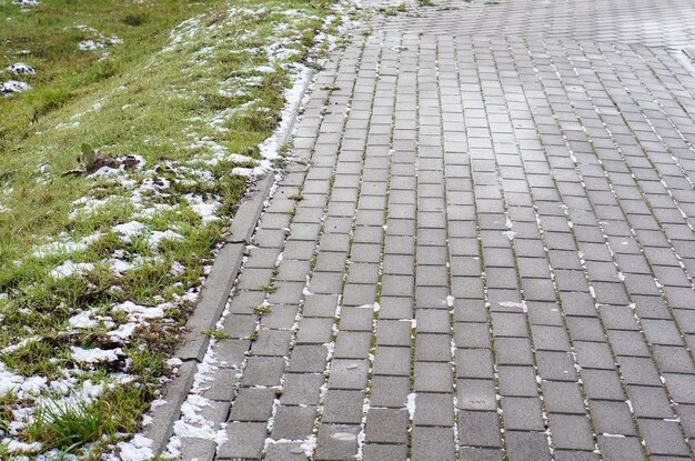 Close-up shot van stenen bestrating gemaakt van blokken naast gras in de winter