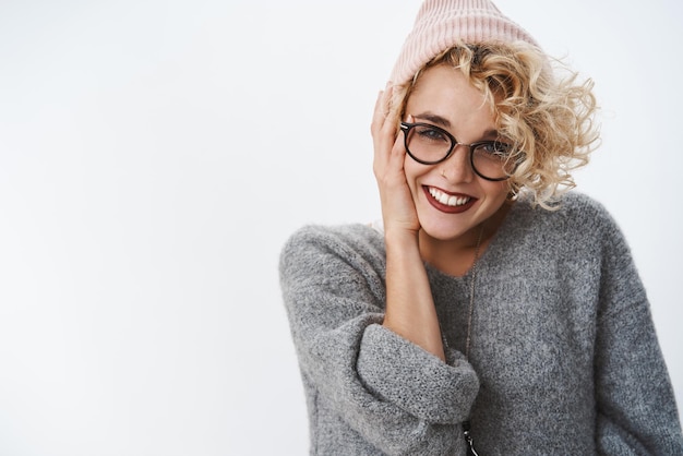 Close-up shot van tedere en sensuele knappe vrouw met blond kapsel en bril met warme wintermuts die geniet van vakantie op een mooie romantische plek die fladdert met vriendje en brutaal giechelt