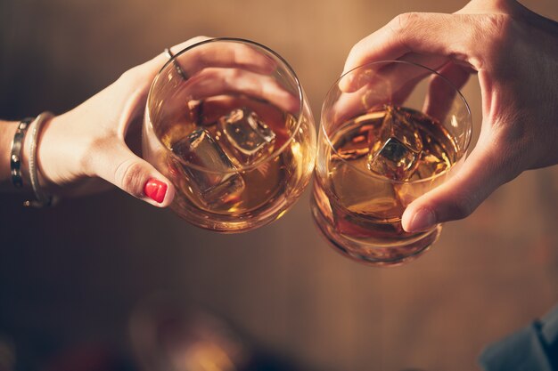 Close-up shot van twee mensen rammelende glazen met alcohol op een toast
