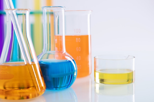 Close-up shot van verschillende kolven met kleurrijke vloeistoffen op een wit oppervlak in een lab
