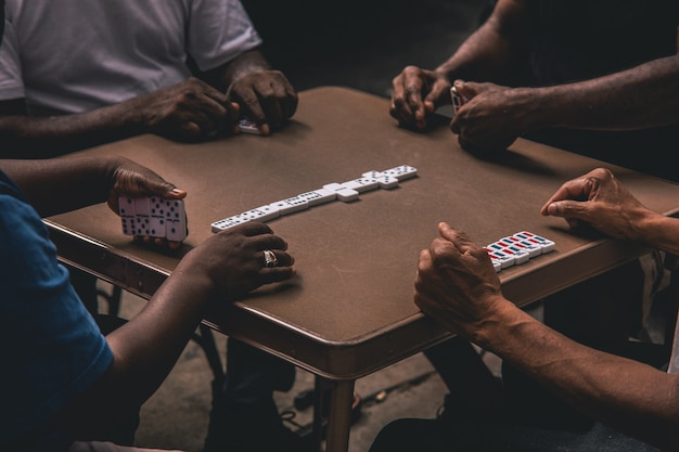 Gratis foto close-up shot van vier afrikaanse mensen spelen van dominostenen rond een tafel