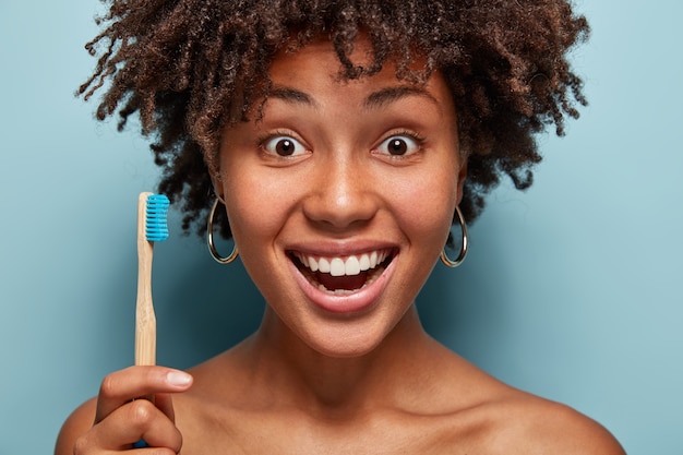 Close-up shot van vrolijke jonge vrouw met een afro poseren in een roze trui