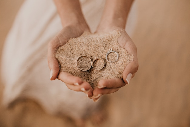 Close-up shot van vrouwelijke handen met zand met drie ringen op de top