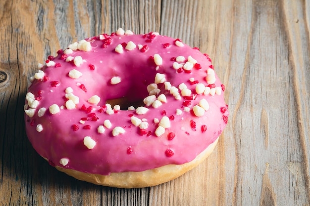 Close-up smakelijke roze donut op een houten achtergrond