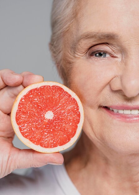 Close-up smiley vrouw met rode sinaasappel