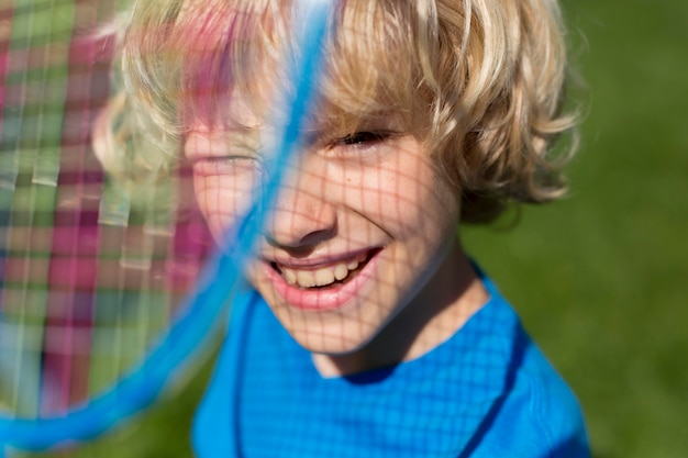 Gratis foto close-up smileyjongen met badmintonracket