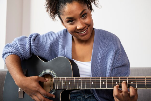 Close-up smileyvrouw die gitaar speelt