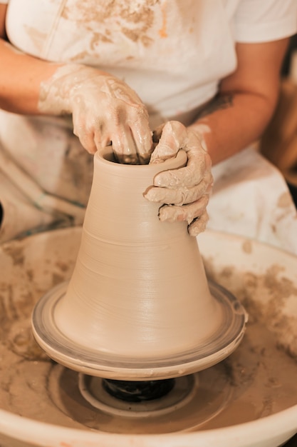 Gratis foto close-up van a maakt een pot klei op een pottenbakkerswiel