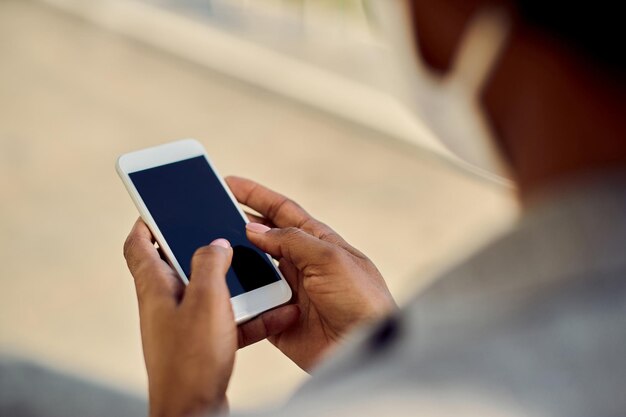 Close-up van Afro-Amerikaanse zakenvrouw sms'en op mobiele telefoon buitenshuis