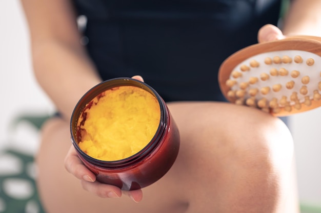Gratis foto close-up van anticellulitis massageborstel en lichaamsscrub in vrouwelijke handen