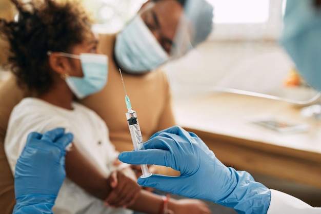 Close-up van arts die vaccin geeft aan een kind in de medische kliniek