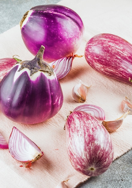 Close-up van aubergines; knoflookteentjes en uien op doek