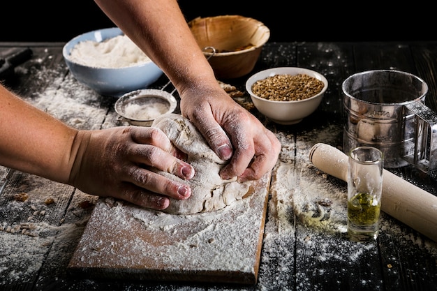 Gratis foto close-up van bakker het kneden van het deeg op hakbord met ingrediënten