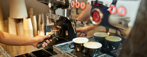 Gratis foto close-up van barista hand en koffiemachine met vers gemalen bonen werken in een café