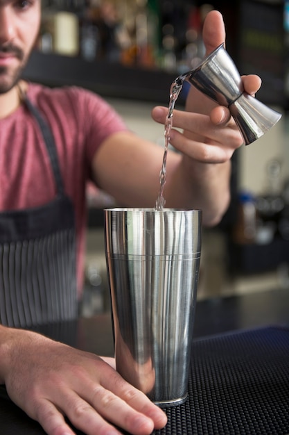 Gratis foto close-up van barman gieten cocktail in shaker aan toog