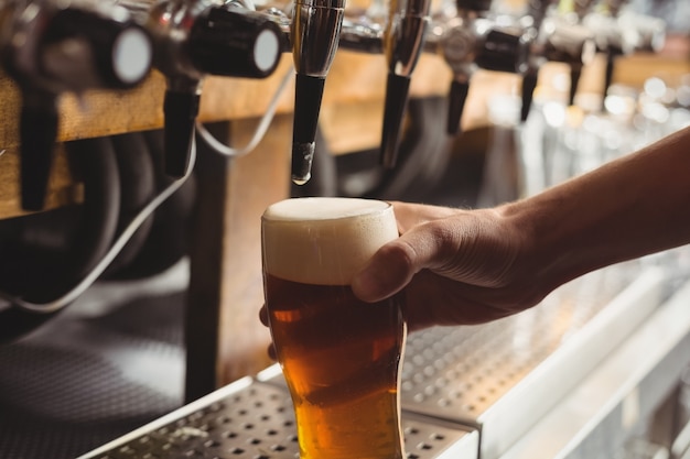 Close-up van barman het vullen bier van barpomp