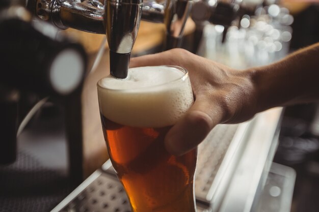 Close-up van barman het vullen bier van barpomp