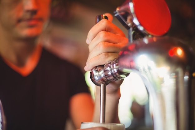 Close-up van barman het vullen bier van barpomp