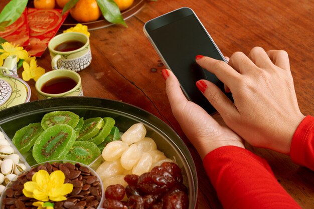 Close-up van bebouwde vrouwelijke handen die smartphone op een gediende dinerlijst houden